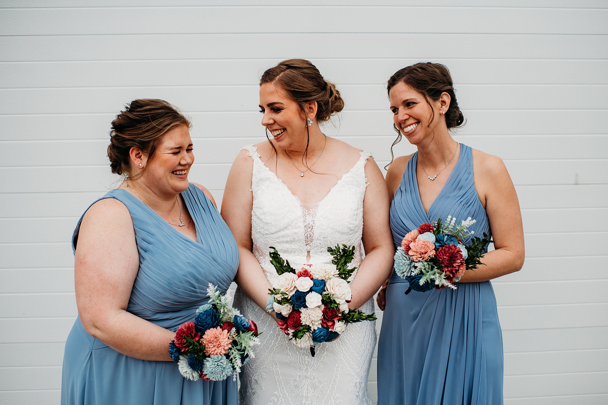 bridal party dressed in powder blue laughing with the bride and holding bouquets at Milwaukee Wedding Venues