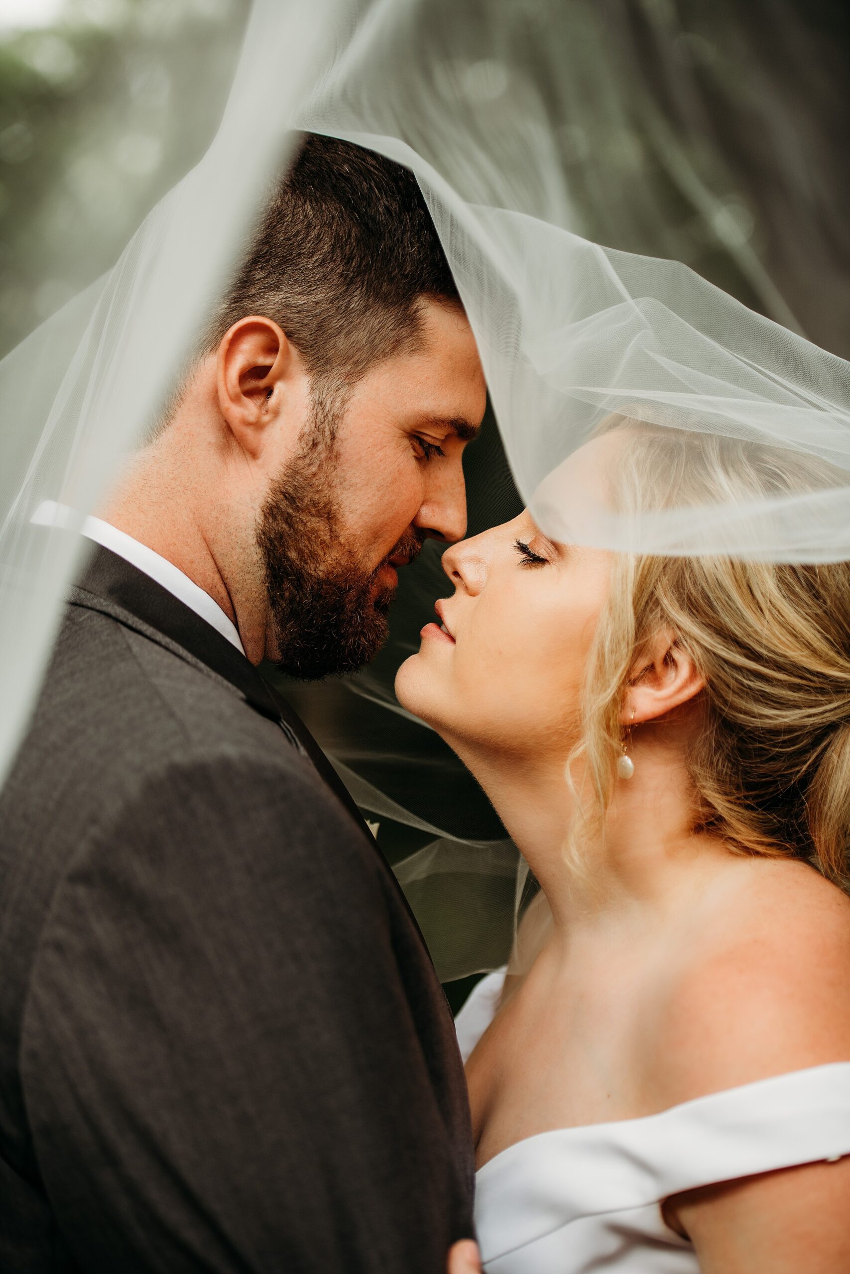 bride with long veil and groom in grey suit leaning in for a kiss at Milwaukee Wedding Venues