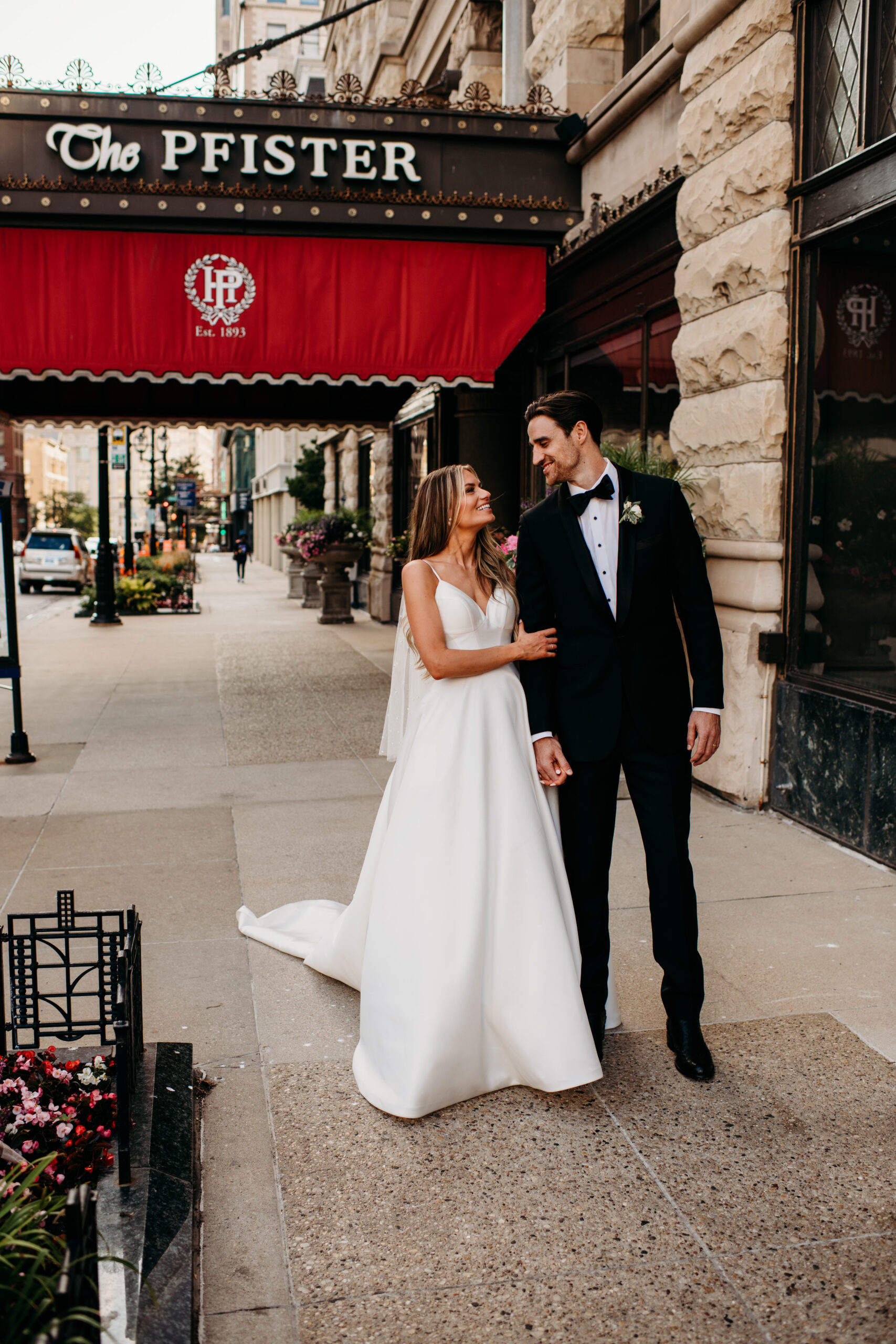 bride and groom in classic black and white wedding attire standing in front of the Pfister Hotel Wedding venue looking at each other