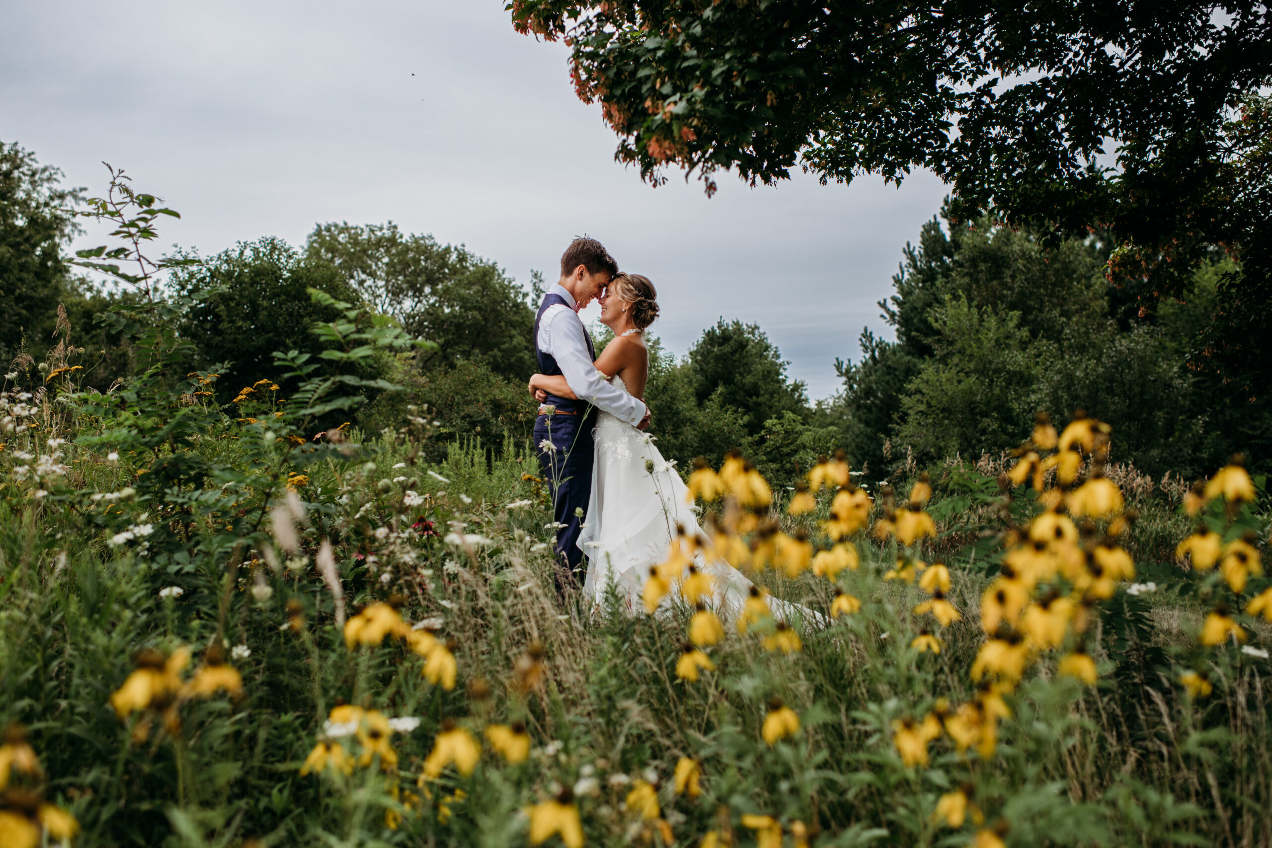 bride and groom holding each other in a field of yellow flowers Wisconsin outdoor wedding venues